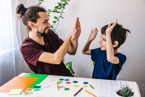 A child behavior specialist does a high-five with an autistic child