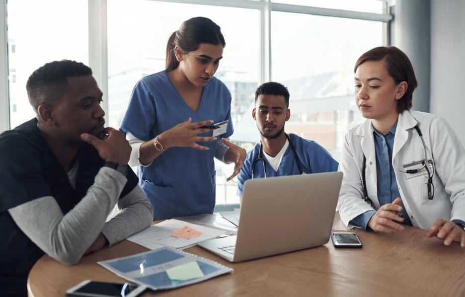 A nurse consults with her colleagues in a hospital meeting room